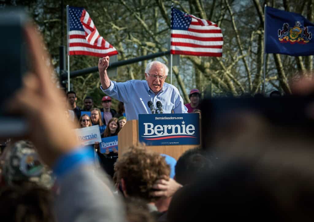 Bernie Sanders standing on lectern surrounded by people