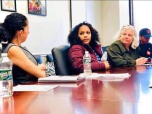 young Black girl sitting at conference room between two women