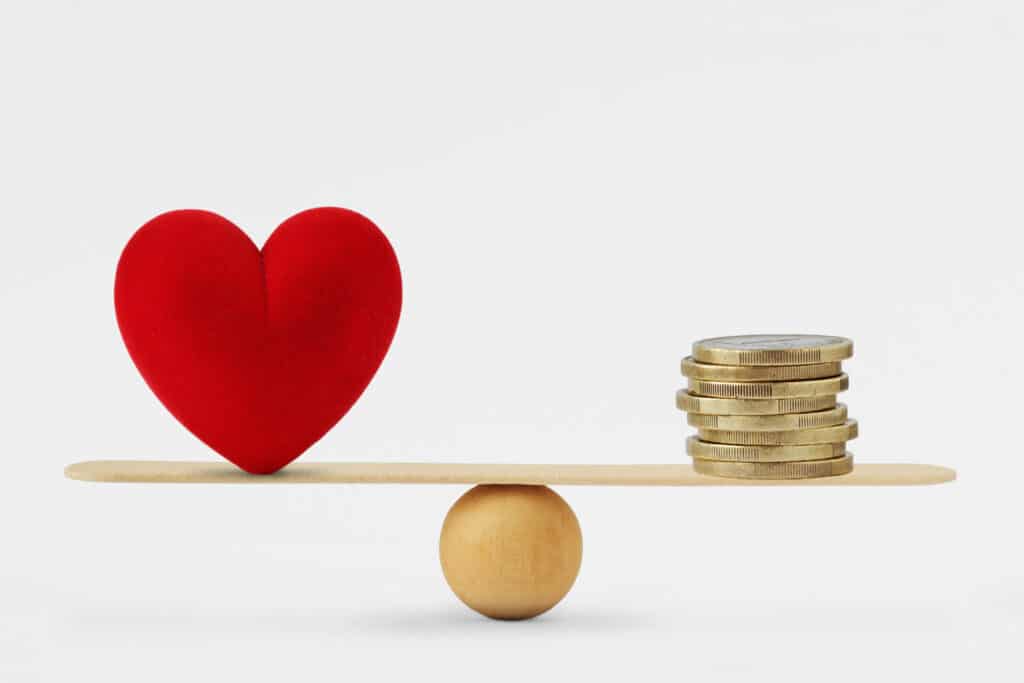 Heart and money on balance scale, showing folks choice between unemployment and grueling reality post-pandemic.