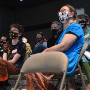 people sitting in a dark auditorium in masks